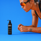 A bottle of GloFuel Body Wash is shown on a bright blue background next to a woman in athletic sunglasses and a black sports top, leaning forward.