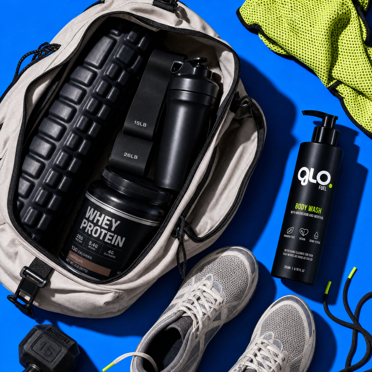 An open beige backpack on a bright blue background displays a black shaker bottle, a black tub of whey protein powder, and a black pump bottle of GLO Fuel body wash, alongside gray athletic shoes and a neon yellow towel.